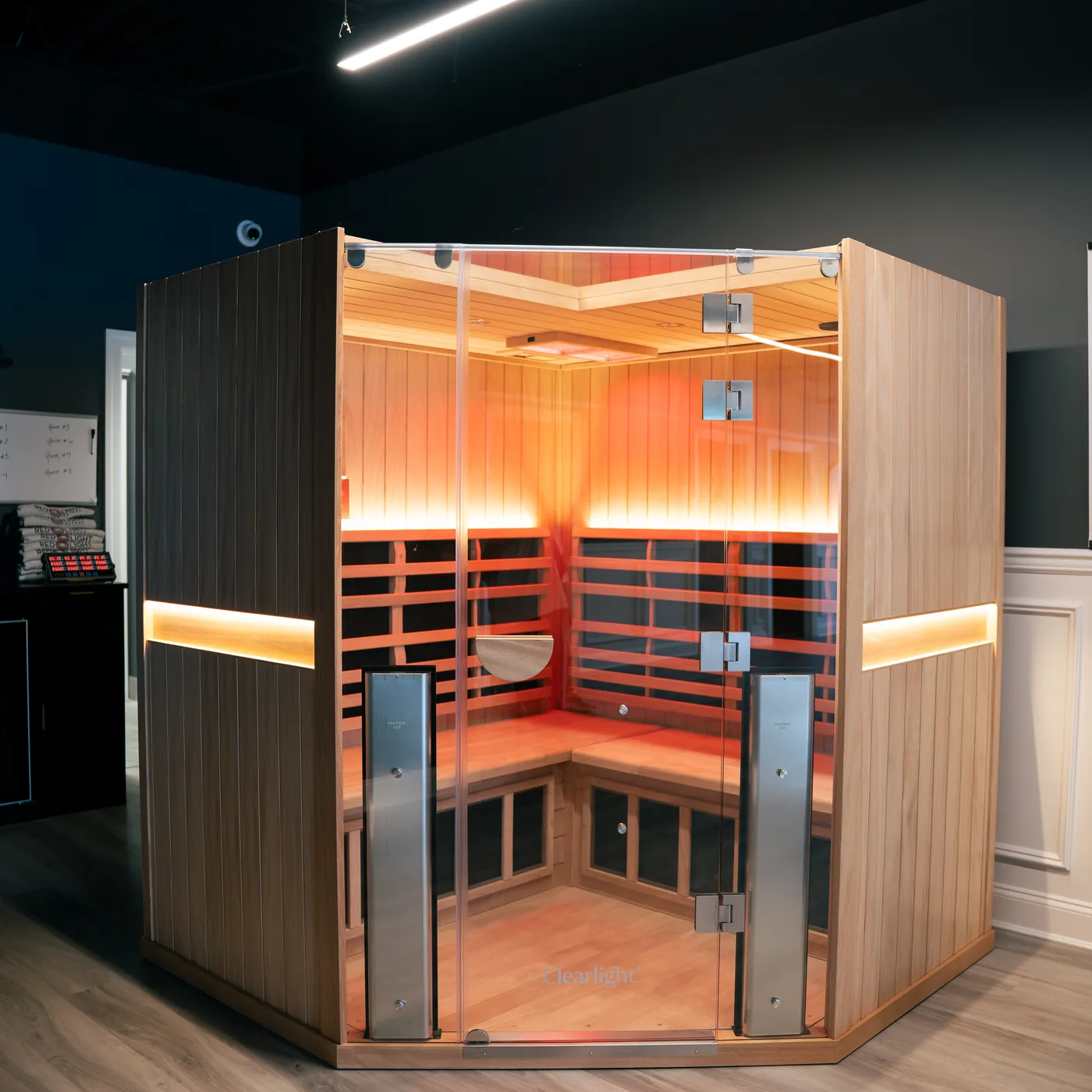 A cedar far infrared sauna cabin with a glass door, glowing warm from within
